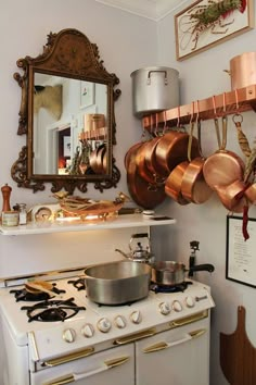 a kitchen with copper pots and pans hanging on the wall next to an oven