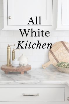 all white kitchen with text overlaying the image and in front of it is a wooden cutting board on a marble countertop