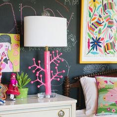 a bedroom decorated in pink and green with pictures on the wall, lamp, and bed