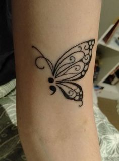 a small butterfly tattoo on the ankle is shown in black and grey ink with swirls