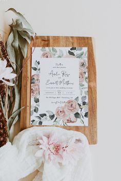 the wedding stationery is surrounded by flowers and greenery, such as eucalyptus leaves