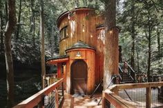 a tree house built into the side of a forest with stairs leading up to it