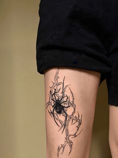 a woman's leg with a spider tattoo on her left thigh and black ink