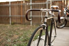 a close up of a bike parked on the side of a road next to a fence