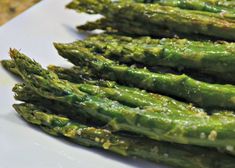 asparagus on a white plate ready to be cooked in the oven with seasoning