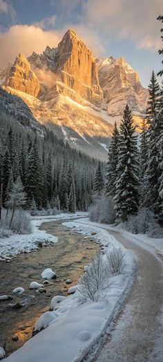 a river running through a snow covered forest next to a lush green hillside with mountains in the background