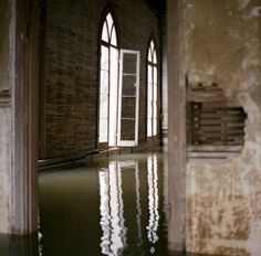 an empty room with water in the floor and two windows on either side of it