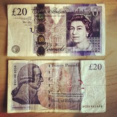 two british pound notes sitting on top of a wooden table