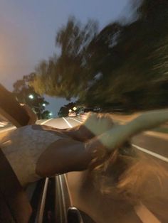 a woman riding in the back of a car with her hand on the steering wheel