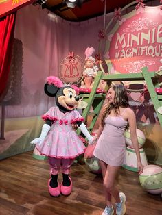 a woman in a pink dress standing next to minnie mouse