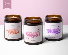 three candles sitting next to each other on top of a white table with pink and purple background