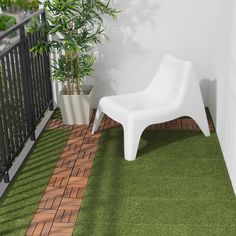 a white chair sitting on top of a grass covered floor next to a potted plant