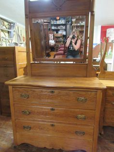 a dresser with a mirror on top of it and a woman taking a photo in the reflection