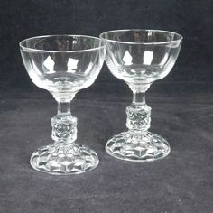 two clear goblets sitting side by side on a black tableclothed surface