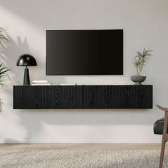 a flat screen tv mounted to the side of a wall next to a chair and potted plant