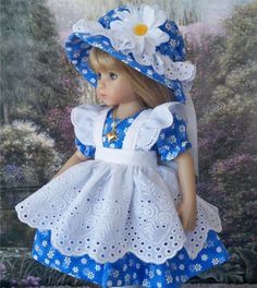 a doll wearing a blue and white dress with flowers on it's head is standing in front of a painting