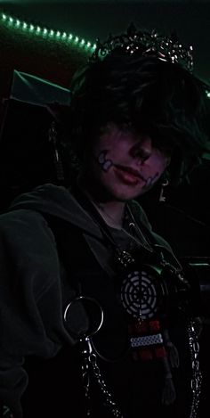 a woman with dark makeup and piercings on her face wearing a chain around her neck