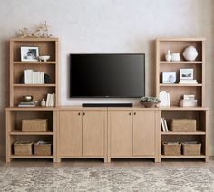 a flat screen tv sitting on top of a wooden entertainment center next to bookshelves