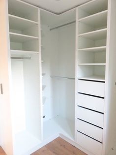 an empty walk in closet with white shelving and wood flooring on the side