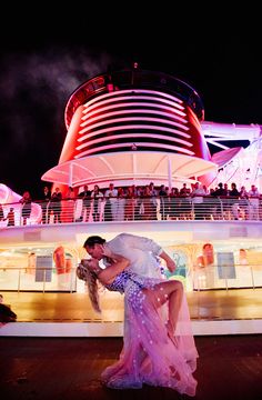 a couple kissing on the deck of a cruise ship at night with fireworks in the background