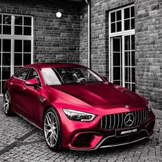 a red car parked in front of a brick building