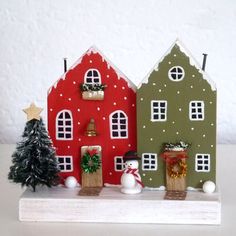 two small houses with snowmen and christmas trees in front of them on a shelf