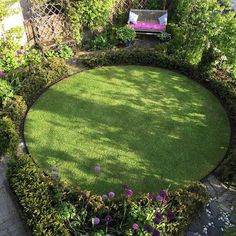 a circular lawn surrounded by bushes and flowers