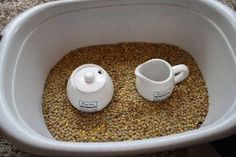 two coffee mugs sitting on top of a bowl filled with beans