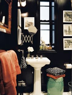 a white sink sitting under a bathroom mirror next to a green pot filled with flowers