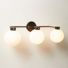 three lights are hanging from the side of a wall mounted light fixture in a bathroom