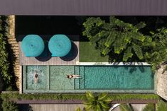 an aerial view of two people swimming in a pool next to some trees and bushes