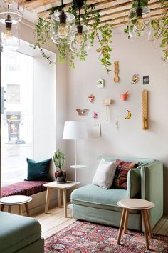 a living room filled with furniture and lots of plants hanging from the ceiling above it