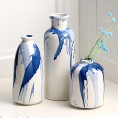 three blue and white vases sitting next to each other on a table with flowers in them