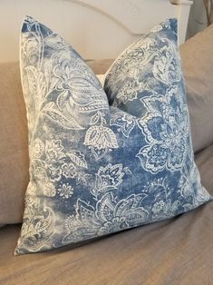 a blue and white pillow sitting on top of a bed