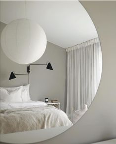 a white bed sitting under a round mirror