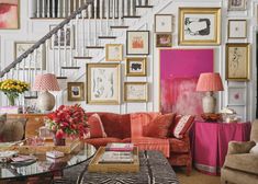 a living room filled with lots of furniture and pictures on the wall next to a stair case