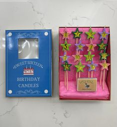 two birthday candles are in a box and one is pink with green stars on them