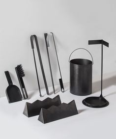 an assortment of kitchen utensils are arranged on a white surface with black accents