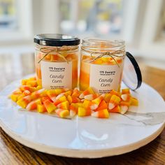 two jars filled with candy corn sitting on top of a white plate