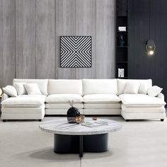 a living room with white couches and a coffee table in front of a gray wall