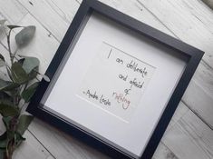 a frame with writing on it sitting next to a potted plant and a vase filled with flowers