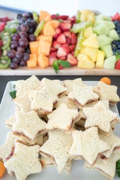 there is a plate full of fruit and crackers next to a platter of grapes