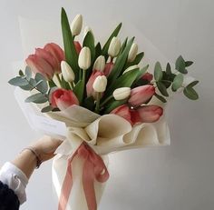 a bouquet of tulips and other flowers is being held by someone's hand