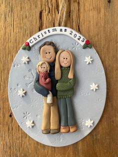 a christmas ornament with two people holding a child