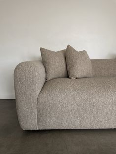 a couch with two pillows on it in front of a white wall and black floor