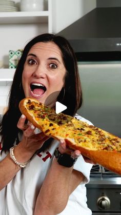 a woman holding up a large piece of pizza