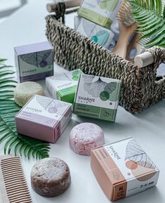 several different types of soaps on a table next to a basket with fern leaves