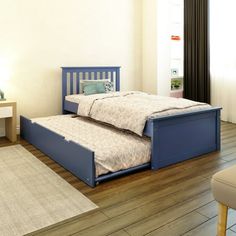 two twin size beds in a room with hardwood floors and white walls, one is blue and the other is beige