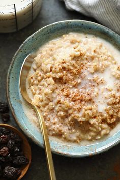 a bowl of oatmeal with raisins and milk on the side