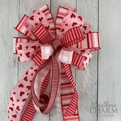 a red and white bow with hearts on it sitting on top of a wooden floor